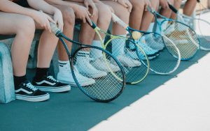 kids sitting down waiting for first tennis lesson