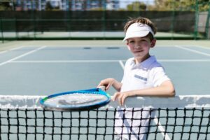 Junior tennis player at the net holding a racquet,, personalised tennis coaching newcastle