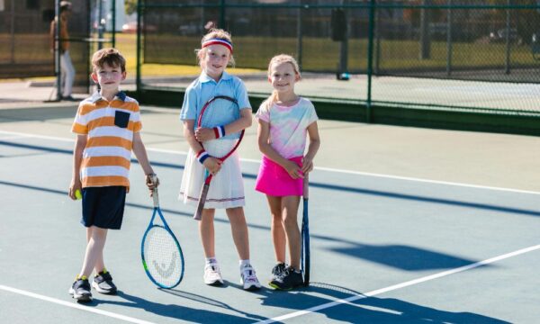 Junior group tennis lesson in Newcastle with three kids holding racquets