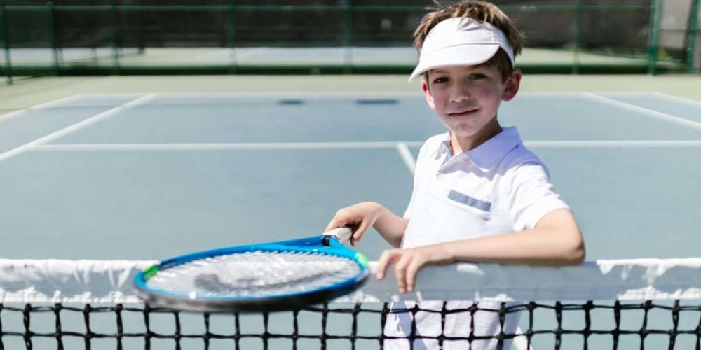 Junior tennis player at the net holding a racquet,, personalised tennis coaching newcastle